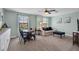 Spacious living room with light green walls, a ceiling fan, big windows, and a seating area with a white sofa at 12515 Horseshoe Bend Dr, Lithia, FL 33547