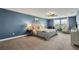 Large bedroom with a tufted headboard, ceiling fan, neutral carpet, and lots of natural light at 12515 Horseshoe Bend Dr, Lithia, FL 33547