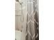 Close-up of tiled shower with glass shelves and a shower curtain with geometric design at 5100 Burchette Rd # 306, Tampa, FL 33647