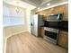 Well-lit kitchen with stainless steel appliances, wood cabinets, granite countertops, and modern flooring at 6315 Shoreline Dr # 3204, Seminole, FL 33708