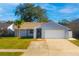 Charming one-story home with a well-manicured lawn, blue paint, and a driveway leading to a two-car garage at 16109 Northglenn Dr, Tampa, FL 33618