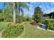 Lush backyard featuring meticulously landscaped areas, healthy green grass, and vibrant plants and trees at 16135 Cape Coral Dr, Wimauma, FL 33598