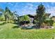 Serene backyard featuring a beautifully landscaped garden, mature trees, and a screened-in lanai for relaxation at 16135 Cape Coral Dr, Wimauma, FL 33598