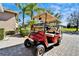 Stylish red golf cart parked on a paved driveway, offering convenient transportation and leisure at 16135 Cape Coral Dr, Wimauma, FL 33598