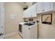 Bright laundry room featuring a modern washer and dryer, storage cabinets, and neutral decor at 16135 Cape Coral Dr, Wimauma, FL 33598