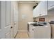 Functional laundry room with white cabinets, modern washer/dryer, and convenient access to an exterior door at 16135 Cape Coral Dr, Wimauma, FL 33598