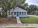 Street view of a cute home with a blue front door, framed by a mature tree and landscaped yard at 301 Mystic Lake N Dr, St Petersburg, FL 33702