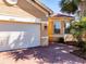 Exterior of a charming single Gathering home featuring a two car garage, a brick driveway and mature landscaping at 4822 Grand Banks Dr, Wimauma, FL 33598
