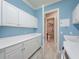 Well-lit laundry room featuring white cabinetry, utility sink, and access to the half-bath at 4822 Grand Banks Dr, Wimauma, FL 33598