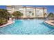 Large community swimming pool at a condo complex with lounge chairs and lush tropical landscaping at 5108 Brittany S Dr # 204, St Petersburg, FL 33715