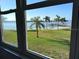 Scenic waterfront view through a large window showing a sandy beach, palm trees, and a boat dock at 5108 Brittany S Dr # 204, St Petersburg, FL 33715