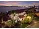 Breathtaking waterfront home with a red tile roof, lush landscaping, and stunning evening sky reflections at 705 Riviera Dunes Way, Palmetto, FL 34221