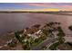 Waterfront neighborhood with luxurious houses featuring red tile roofs and lush tropical landscaping at sunset at 705 Riviera Dunes Way, Palmetto, FL 34221