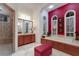 Elegant bathroom with modern fixtures, red accent wall, and large soaking tub with shuttered windows at 705 Riviera Dunes Way, Palmetto, FL 34221