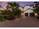 Elegant two-story home featuring a clay tile roof, brick driveway, and lush tropical landscaping at 705 Riviera Dunes Way, Palmetto, FL 34221
