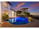 Beautiful kidney shaped pool with lit palms, rock features, and brick patio at 705 Riviera Dunes Way, Palmetto, FL 34221