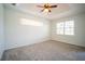 Bright bedroom with carpeted floors, tray ceiling, a fan, and large windows, offering a serene retreat at 11713 Summer Springs Dr, Riverview, FL 33579