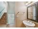 Stylish half bath featuring pedestal sink, decorative mirror and staircase access at 2508 W Shell Point Rd, Tampa, FL 33611