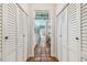 Hallway with white shutter doors leading to a kitchen featuring terracotta tile floors and modern appliances at 2508 W Shell Point Rd, Tampa, FL 33611