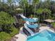 Aerial view of a waterslide tower near the pool, surrounded by lush trees and lounge seating at 3000 Sunwatch, Wesley Chapel, FL 33544