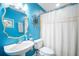 Bright blue bathroom with a white toilet, sink, gold-trimmed mirror, and a white shower curtain at 6411 Grenada Island Ave, Apollo Beach, FL 33572