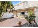 Back patio featuring brick pavers, privacy fence, tropical plants, and sliding glass door entry to home at 6980 Ulmerton Rd # 8C, Largo, FL 33771