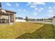 A spacious backyard featuring a well-maintained lawn, white fence, pond view, and a screened-in patio at 19429 Paddock View Dr, Tampa, FL 33647