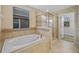 Modern bathroom with large tub, tiled walls, glass-enclosed shower, and natural light at 19429 Paddock View Dr, Tampa, FL 33647