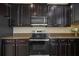 Gourmet kitchen features stainless steel oven and range hood, and dark wood cabinetry at 19429 Paddock View Dr, Tampa, FL 33647