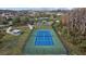 Aerial view of a well-maintained tennis court with green and blue surface, black fence, and a community in the background at 19429 Paddock View Dr, Tampa, FL 33647