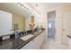 Bright bathroom showcasing double sinks, granite countertops, and a glass-enclosed shower with white cabinets at 3410 Sondrio Cir, Tampa, FL 33611