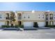 Street view of multi-level townhomes featuring attached garages, neutral color scheme, and mature landscaping at 3410 Sondrio Cir, Tampa, FL 33611