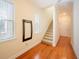 Hallway with hardwood floors leads to a carpeted staircase and white doors at 3410 Sondrio Cir, Tampa, FL 33611