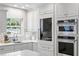Bright kitchen featuring white cabinetry, stainless steel appliances, mosaic backsplash, and quartz countertops at 4810 W San Miguel St, Tampa, FL 33629