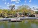 Waterfront backyard featuring tropical landscaping, a wooden dock and a concrete seawall at 4811 Paradise S Way, St Petersburg, FL 33705