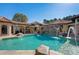 Backyard resort-style pool with rock waterfall feature and covered lounging areas surrounded by green trees at 11158 Warm Wind Way, Weeki Wachee, FL 34613