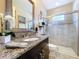 Bathroom featuring granite counters, glass shower and dark wood cabinets at 2385 Arboretum Dr, Palm Harbor, FL 34683