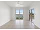 An empty room featuring neutral tones, tile floors, a large window with water views, and sliding doors to a balcony at 4993 Bacopa S Ln # 304, St Petersburg, FL 33715