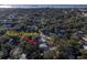 An aerial view of a neighborhood showing the property nestled among mature trees with views of the water in the distance at 817 Wilkie St, Dunedin, FL 34698