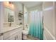 Bathroom featuring a vanity with white cabinets and quartz countertop and shower/tub with blue ombre curtain at 817 Wilkie St, Dunedin, FL 34698
