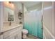 Bathroom featuring a vanity with white cabinets and quartz countertop and shower/tub with blue ombre curtain at 817 Wilkie St, Dunedin, FL 34698