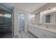 Bathroom with double vanity, white cabinets, quartz countertops, and a tiled shower with glass door at 817 Wilkie St, Dunedin, FL 34698