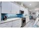 Bright kitchen with white cabinetry, stainless steel appliances, marble countertops, and view into dining area at 817 Wilkie St, Dunedin, FL 34698