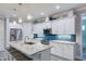 Modern kitchen with stainless steel appliances, white cabinetry, and an island with marble countertop and seating at 817 Wilkie St, Dunedin, FL 34698