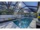 Screened pool area with lanai, outdoor furnishings, tiled deck and lush tropical landscape at 817 Wilkie St, Dunedin, FL 34698