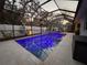 Inviting screened-in pool with ambient lighting, set in a beautifully landscaped backyard with lounge area at 817 Wilkie St, Dunedin, FL 34698