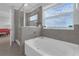 Luxurious bathroom featuring a soaking tub, glass-enclosed shower, and large windows at 10944 Delta Huff Ct, San Antonio, FL 33576