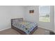 Bright bedroom features a comfortable bed with a colorful patchwork quilt and natural light from a large window at 10944 Delta Huff Ct, San Antonio, FL 33576