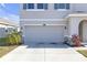 Garage with a concrete driveway and well manicured lawn with a stone-accented facade at 10944 Delta Huff Ct, San Antonio, FL 33576