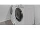Laundry area includes white, front load washer and dryer on gray tiled floor at 10944 Delta Huff Ct, San Antonio, FL 33576